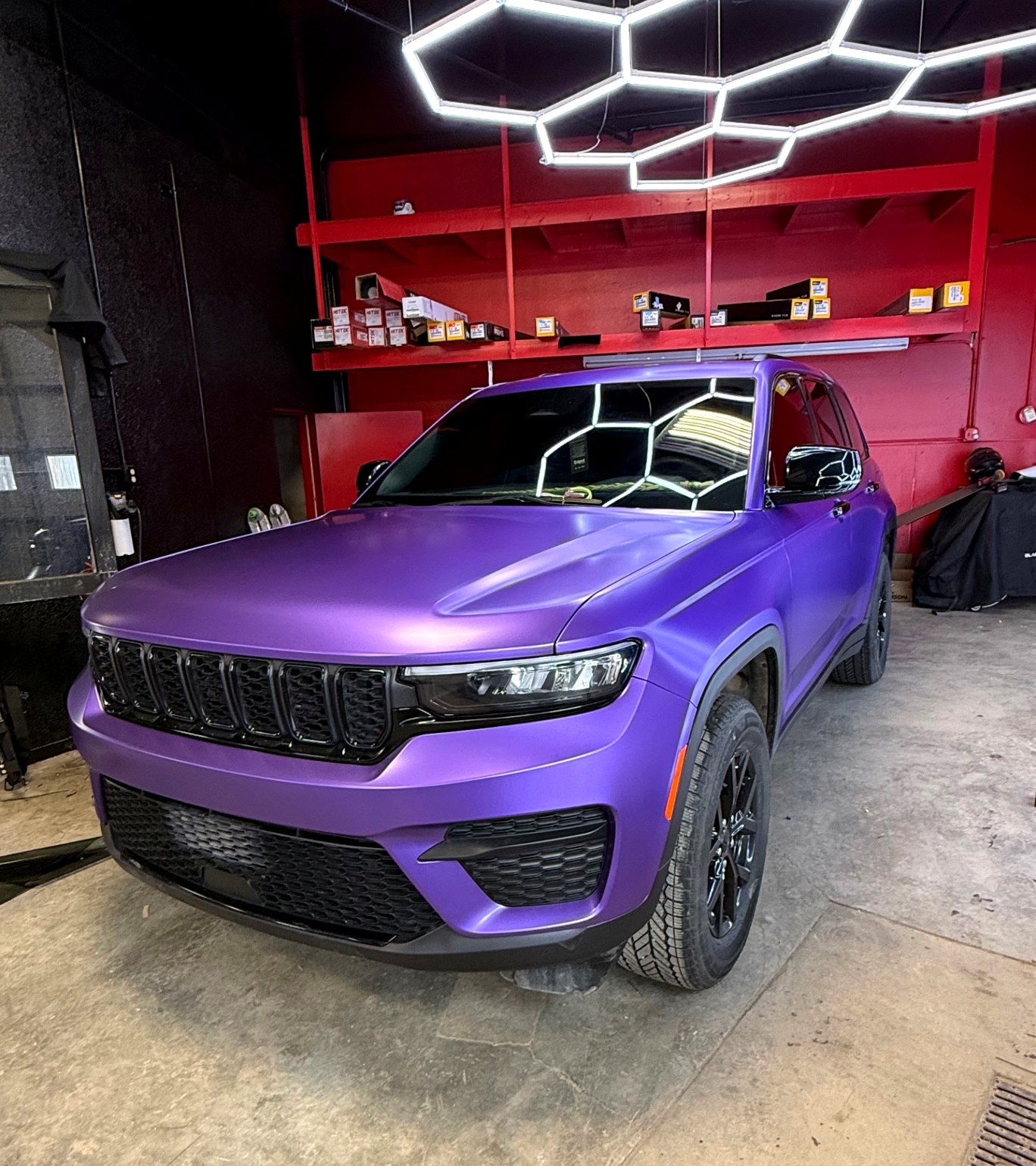 Satin purple wrapped Jeep Grand Cherokee under hexagon shop lights